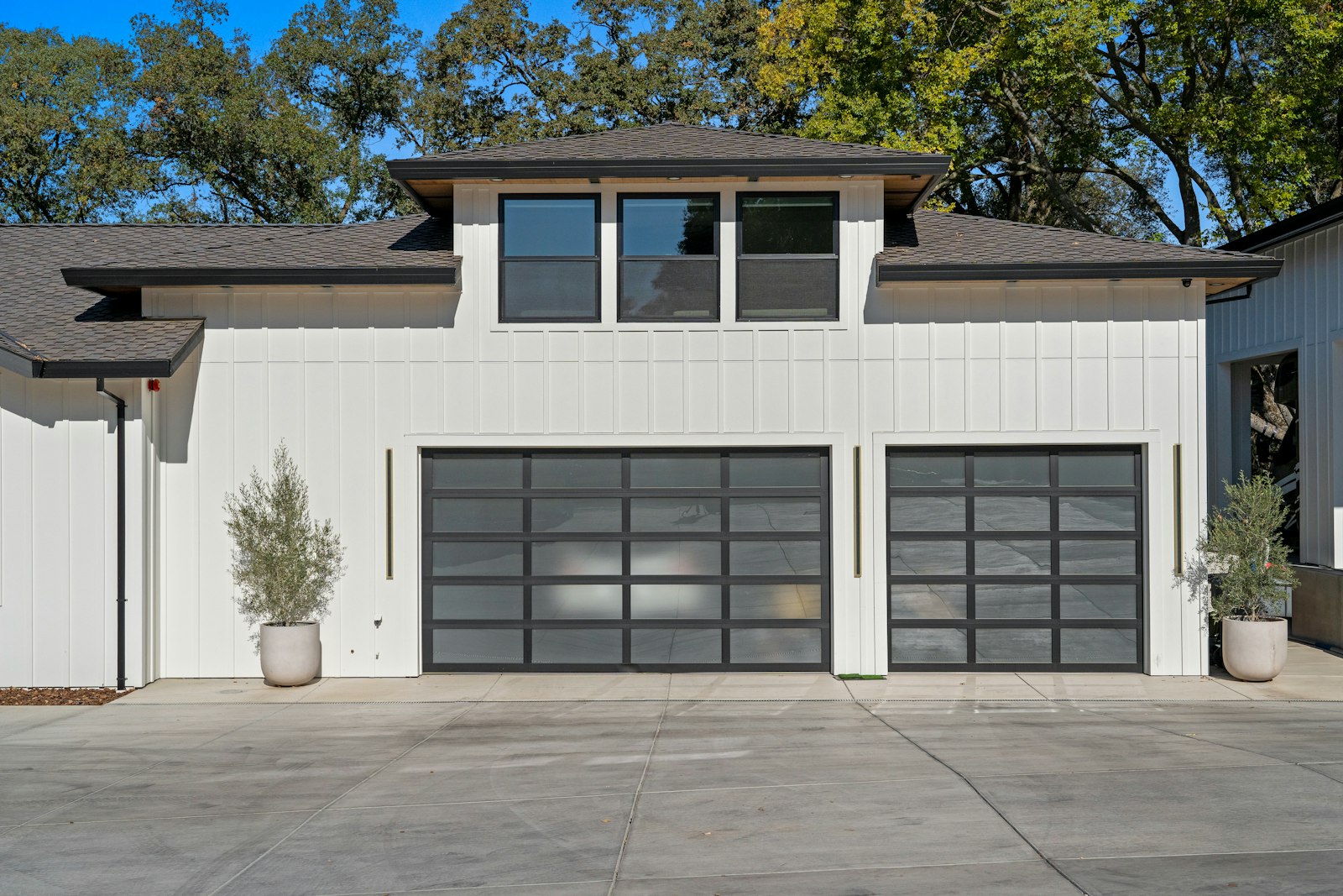 Two modern garage doors on a white house in daylight