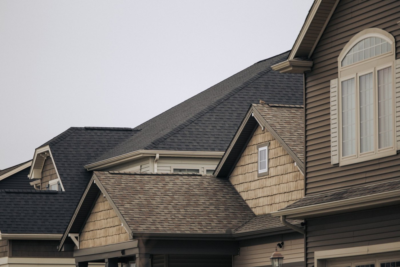 A row of houses with brown asphalt shingle roofs and white windows
