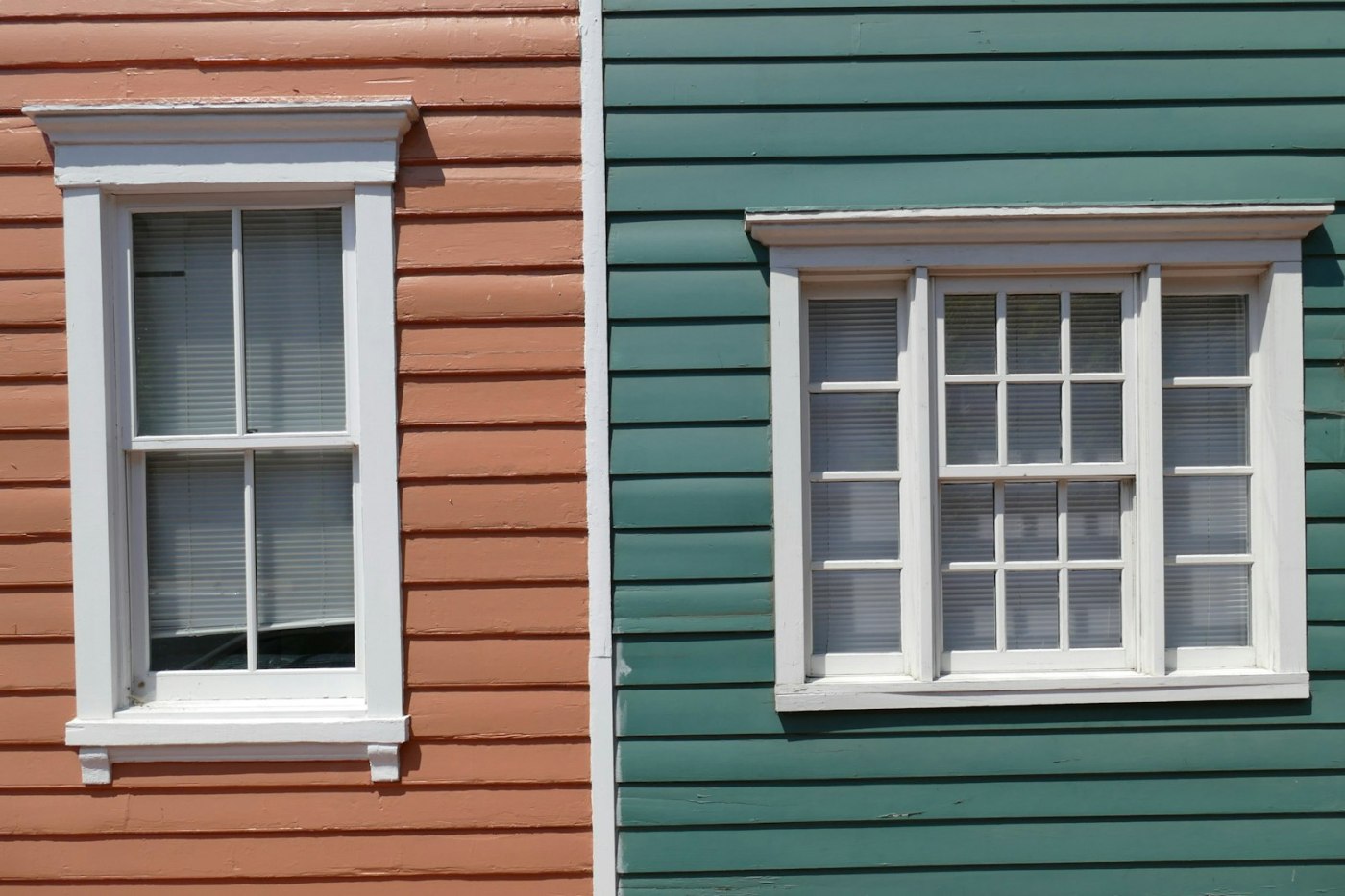 Two adjoining painted house fronts with rows of white-framed sash windows